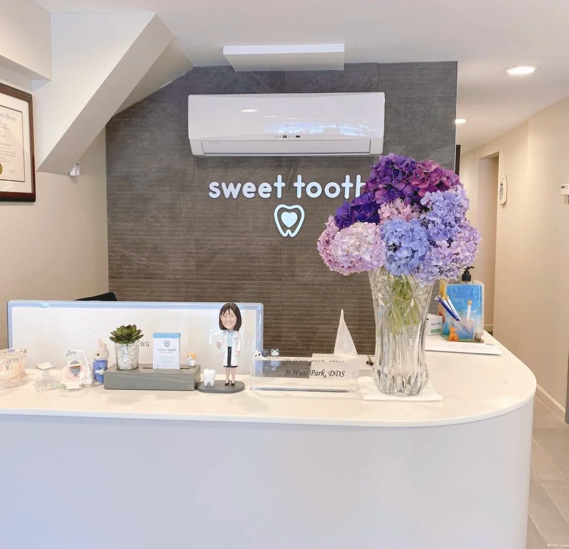 Sweet Tooth Dental Care reception desk with flowers and office signage in a welcoming dental office.