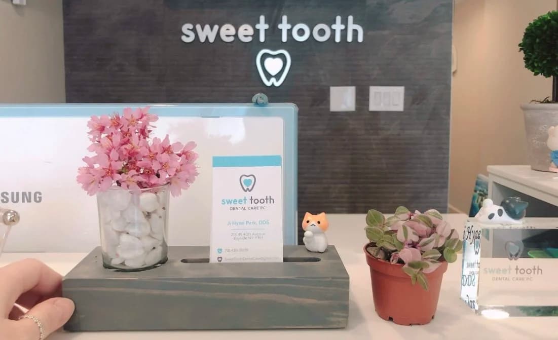 Welcoming front desk area at Sweet Tooth Dental Care with flowers, plants, and office signage.